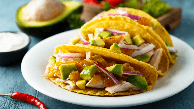 chicken avocado tacos served on a white plate on rustic gray wooden table