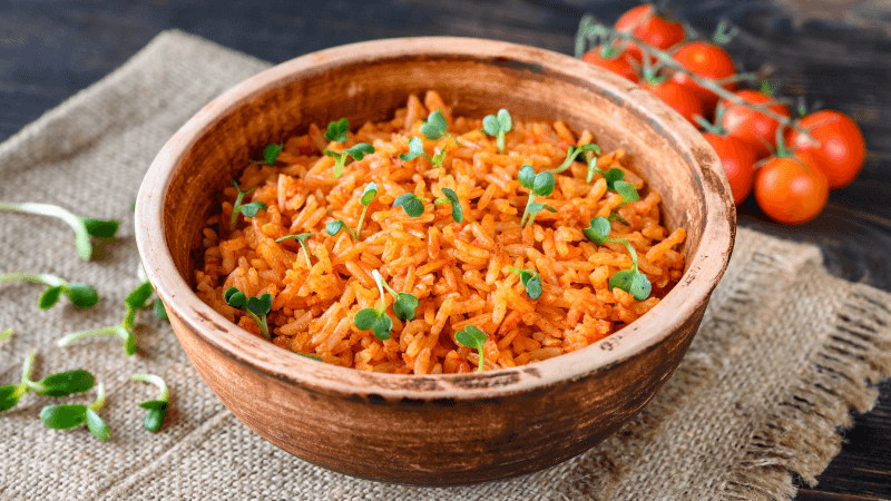 mexican inspried rice served in a bowl with cherry tomatoes by side