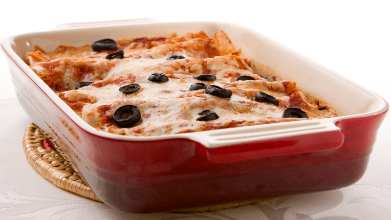 freshly baked enchiladas in a red tray topped with olives