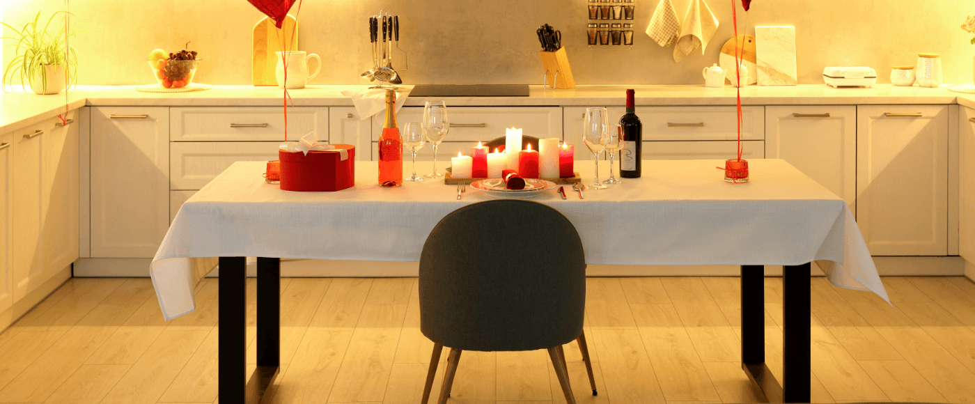 romantic dinner setup with candles, wine & a table for two with white tablecloth