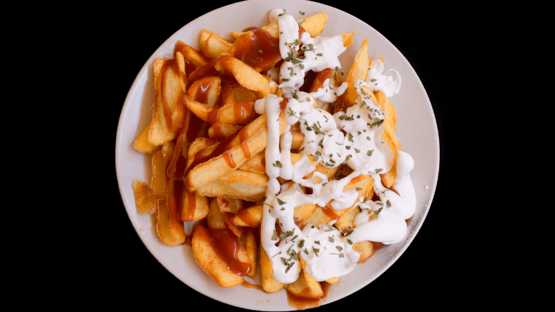 a plate full of mexican fries topped with tomato salsa & sour cream